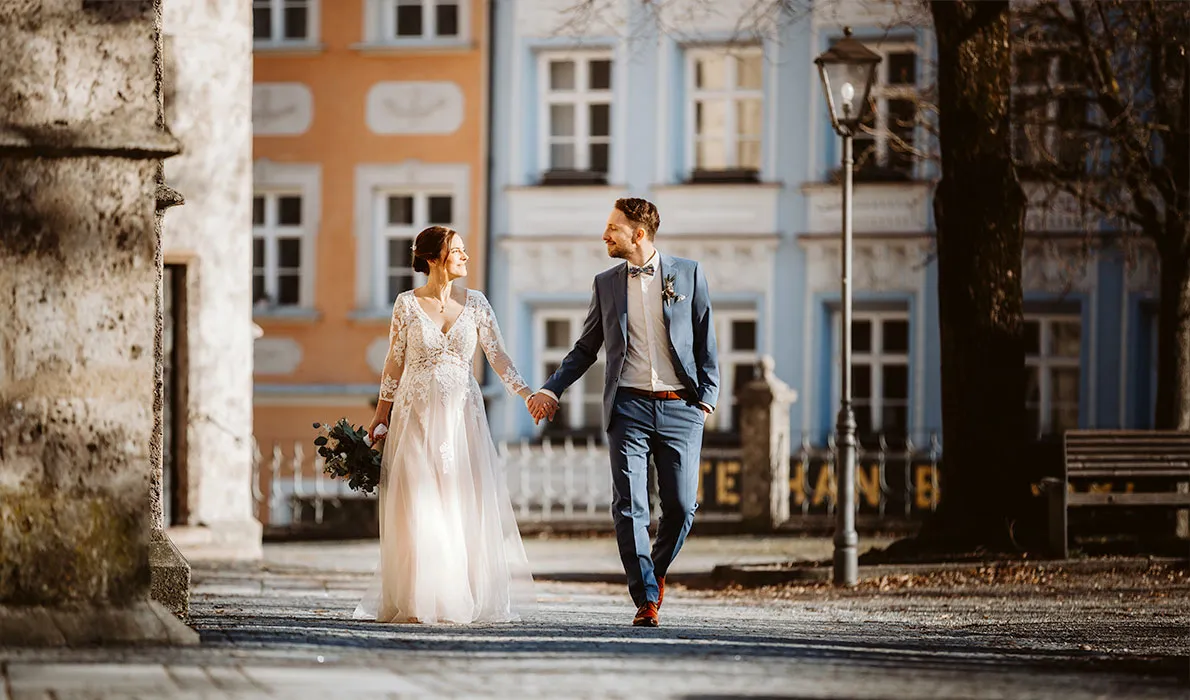 Ein frisch verliebtes Brautpaar geht Hand und Hand durch die Altstadt von Burghausen