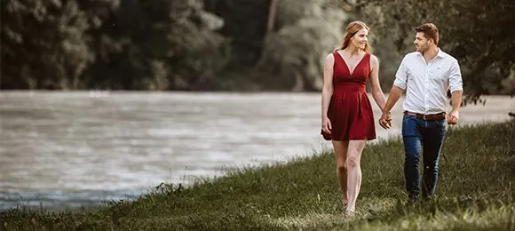 Ein verlobtes Paar läuft Hände haltend am Ufer in Wasserburg am Inn